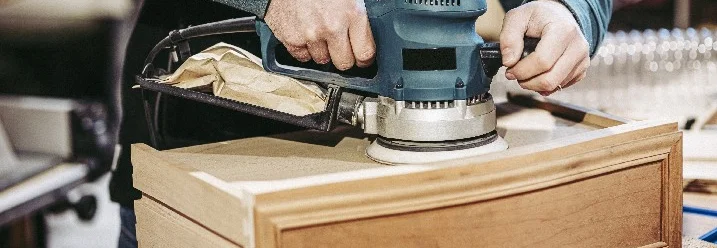 Person schleift Holz mit einem Winkelschleifer